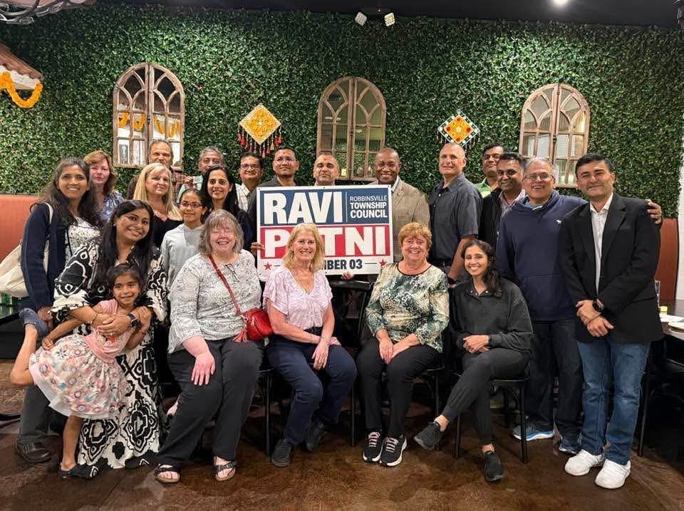 Ravi Patni with a group of neighbors and supporters holding a Ravi Patni for Robbinsville Township Council sign at Ganga Indian Restaurant