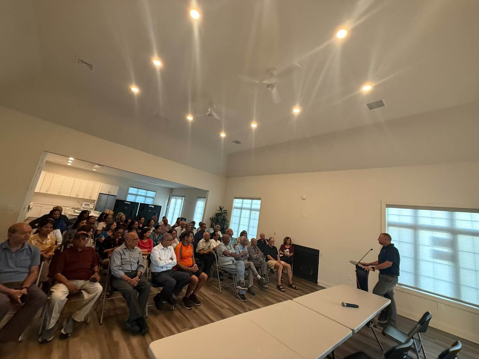Ravi Patni speaking at a podium to a full room of residents in the Raajipo at Robbinsville clubhouse